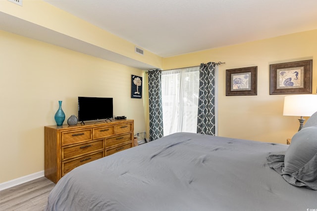 bedroom featuring visible vents, light wood-type flooring, and baseboards