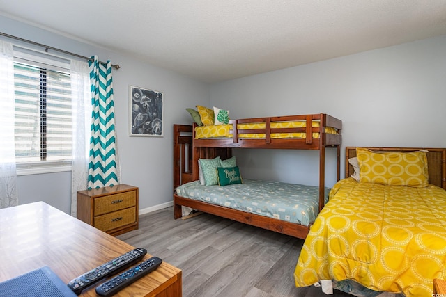 bedroom featuring wood finished floors, baseboards, and a textured ceiling