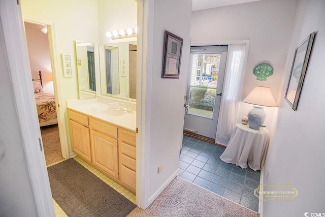 bathroom with tile patterned flooring, vanity, baseboards, and ensuite bathroom