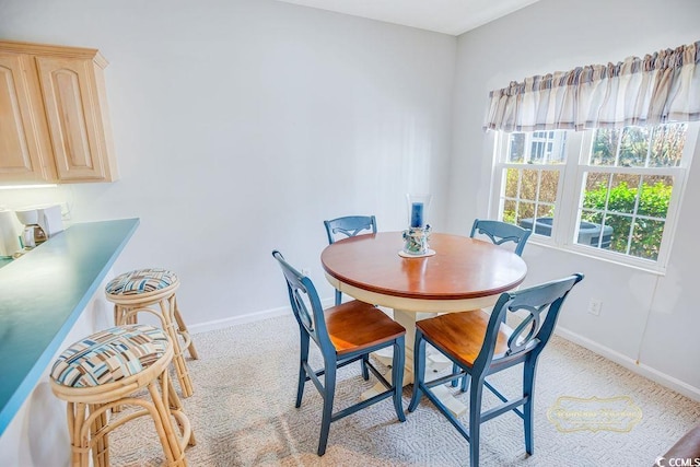 dining area with baseboards and light colored carpet