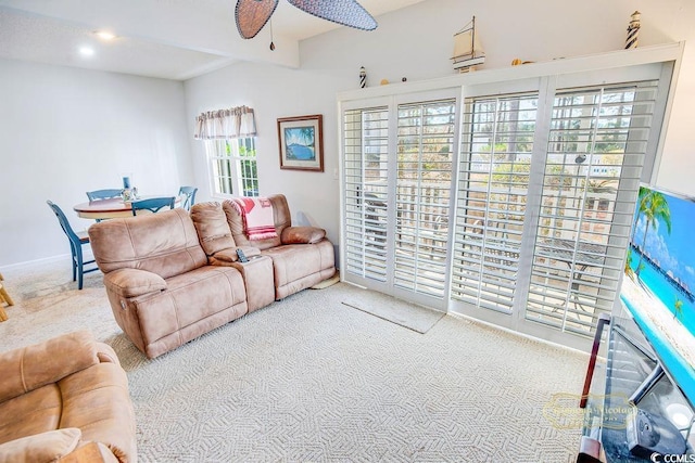 living area with beam ceiling, carpet flooring, and ceiling fan