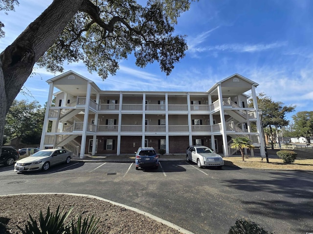 view of property featuring uncovered parking and stairs