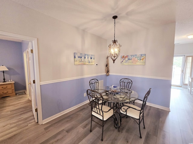 dining room with a chandelier, wood finished floors, and baseboards