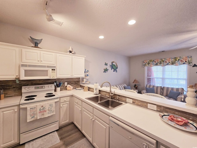 kitchen with light countertops, backsplash, white cabinetry, a sink, and white appliances