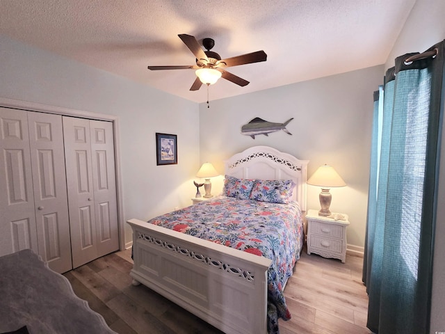 bedroom with a closet, ceiling fan, a textured ceiling, wood finished floors, and baseboards