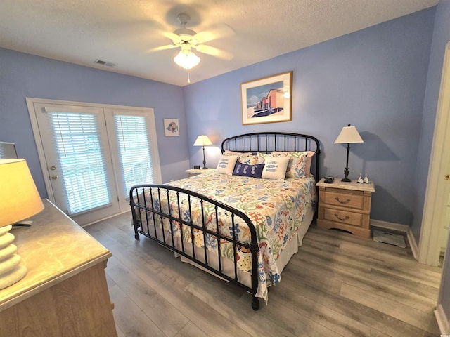 bedroom with access to exterior, visible vents, ceiling fan, wood finished floors, and baseboards