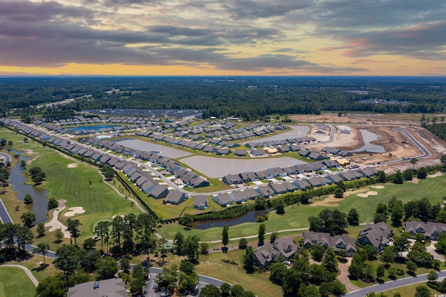 aerial view at dusk featuring a water view, a residential view, and golf course view