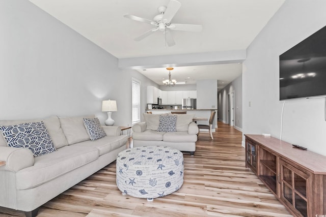 living room featuring light wood-style floors, ceiling fan with notable chandelier, and baseboards