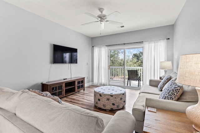 living area with visible vents, baseboards, a ceiling fan, and wood finished floors