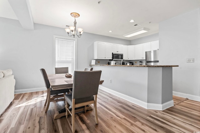dining area with light wood-style flooring, recessed lighting, an inviting chandelier, and baseboards