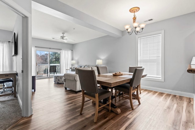 dining space featuring wood finished floors, ceiling fan with notable chandelier, baseboards, and visible vents
