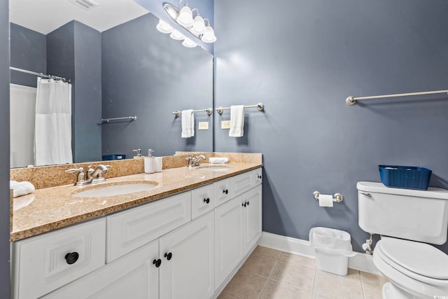 bathroom featuring toilet, a sink, tile patterned flooring, and baseboards