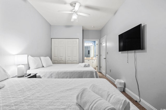 carpeted bedroom with a closet, ensuite bathroom, baseboards, and ceiling fan