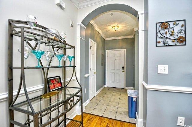 tiled entryway featuring ornamental molding, arched walkways, and baseboards