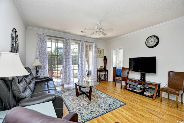 living area with a textured ceiling, ornamental molding, wood finished floors, and a ceiling fan