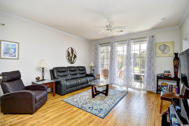 living room with crown molding, visible vents, a ceiling fan, and wood finished floors