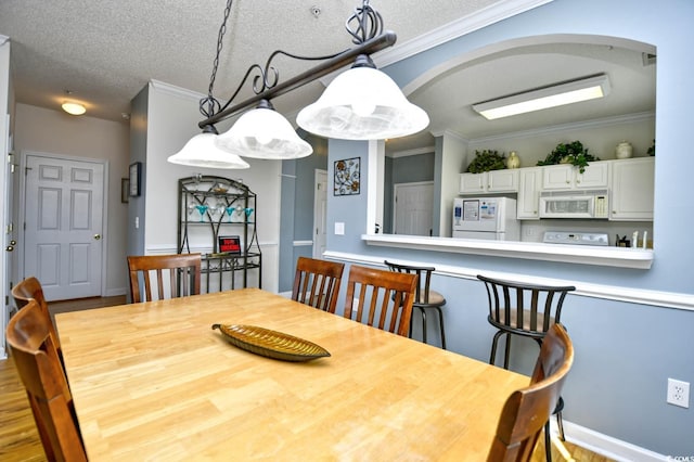 dining area with ornamental molding, arched walkways, and a textured ceiling