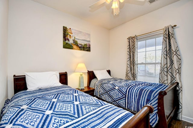 bedroom featuring a ceiling fan, visible vents, baseboards, and wood finished floors