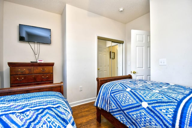 bedroom featuring dark wood-type flooring, a textured ceiling, and baseboards