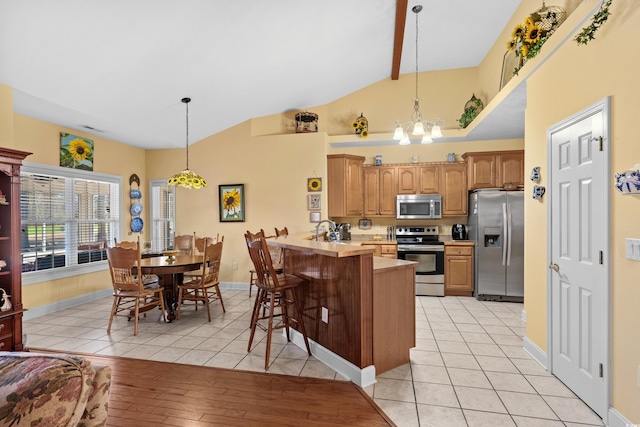 kitchen with a kitchen breakfast bar, a peninsula, stainless steel appliances, light countertops, and a chandelier