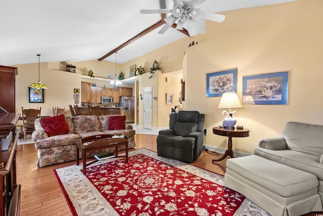 living area with lofted ceiling, light wood finished floors, ceiling fan, and baseboards