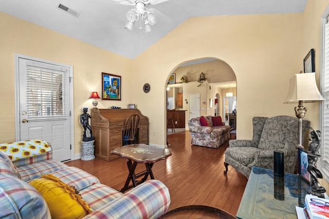 living room with arched walkways, ceiling fan, wood finished floors, visible vents, and vaulted ceiling