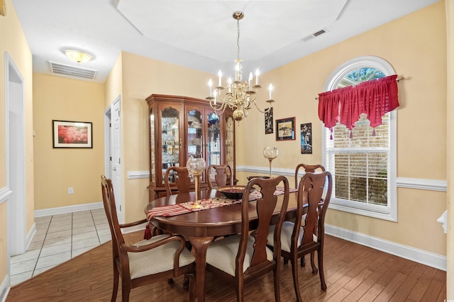 dining area featuring light wood-type flooring, baseboards, visible vents, and a chandelier