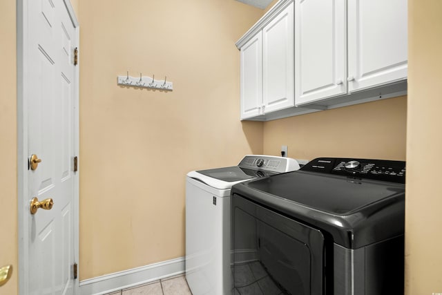 clothes washing area featuring tile patterned flooring, washing machine and clothes dryer, cabinet space, and baseboards