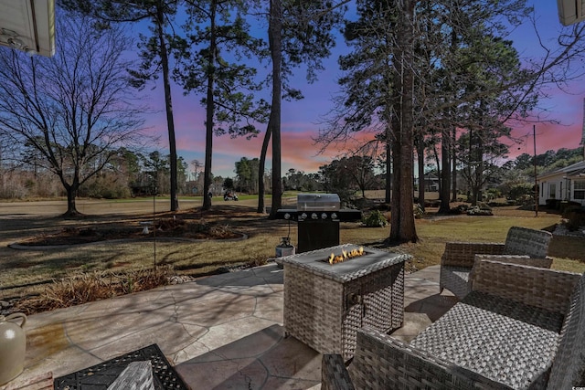 patio terrace at dusk with an outdoor fire pit and a grill