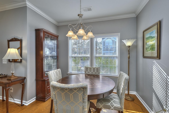 dining space featuring a notable chandelier, light wood finished floors, visible vents, ornamental molding, and baseboards