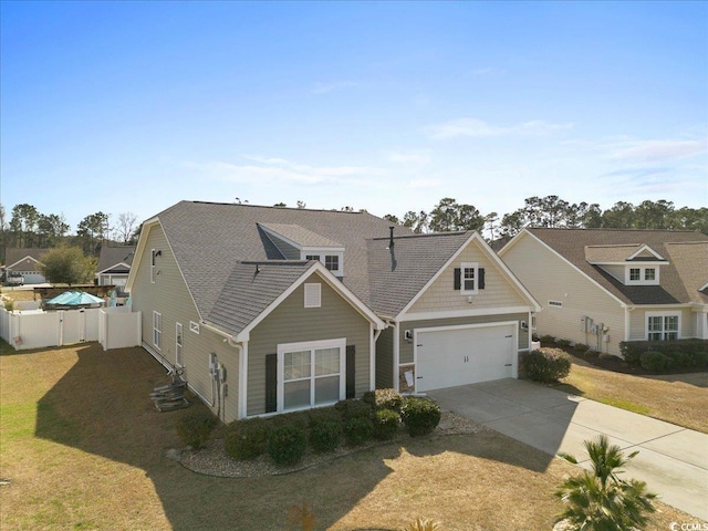 view of front facade featuring driveway, a garage, fence, and a front yard