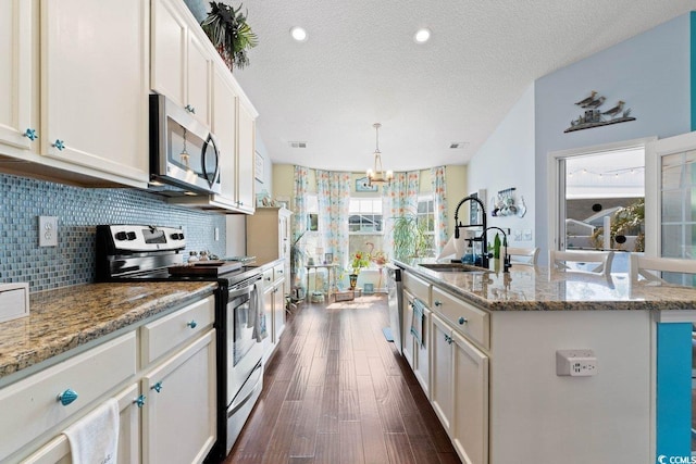 kitchen featuring dark wood-style flooring, a sink, stainless steel appliances, a textured ceiling, and backsplash