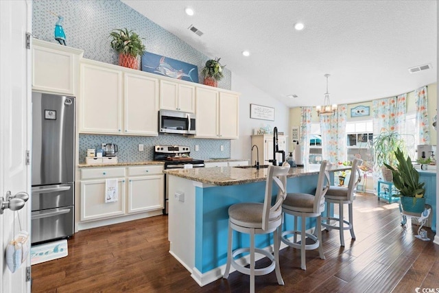 kitchen with appliances with stainless steel finishes, visible vents, vaulted ceiling, and dark wood-type flooring