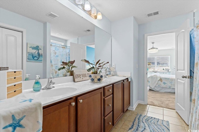 ensuite bathroom with double vanity, tile patterned flooring, a sink, and visible vents