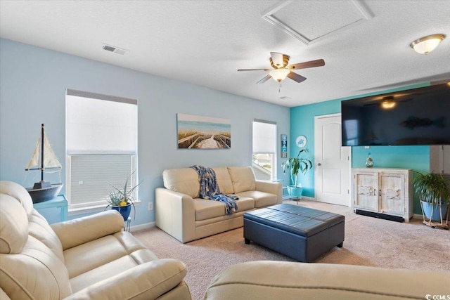 carpeted living area featuring a textured ceiling, baseboards, visible vents, and attic access