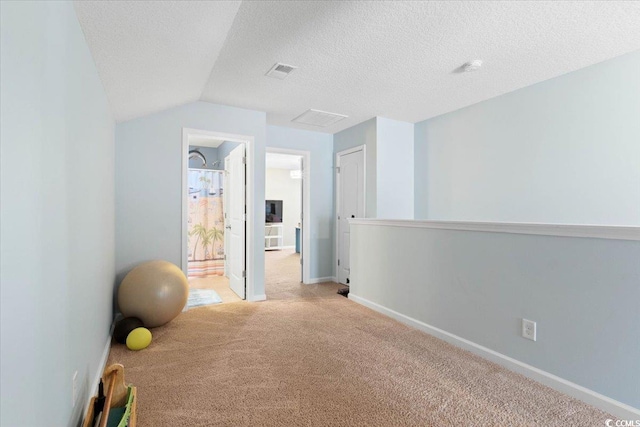 workout area with baseboards, visible vents, a textured ceiling, and light colored carpet