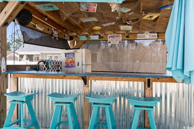 bar featuring a sink and freestanding refrigerator