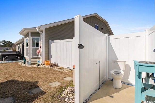 view of home's exterior with a sink and fence