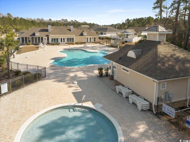 pool with a patio area, fence, and a community hot tub