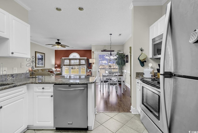 kitchen featuring crown molding, appliances with stainless steel finishes, ceiling fan with notable chandelier, a peninsula, and white cabinetry