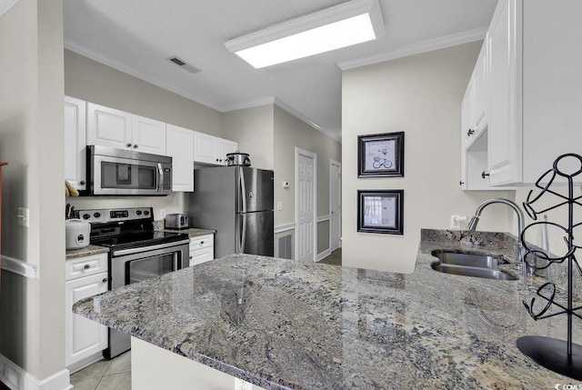 kitchen featuring ornamental molding, a peninsula, stone countertops, a sink, and appliances with stainless steel finishes
