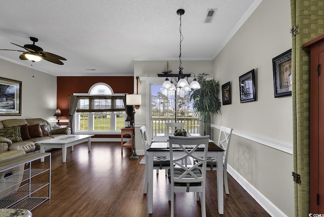 dining space featuring crown molding, dark wood-style flooring, ceiling fan with notable chandelier, and visible vents