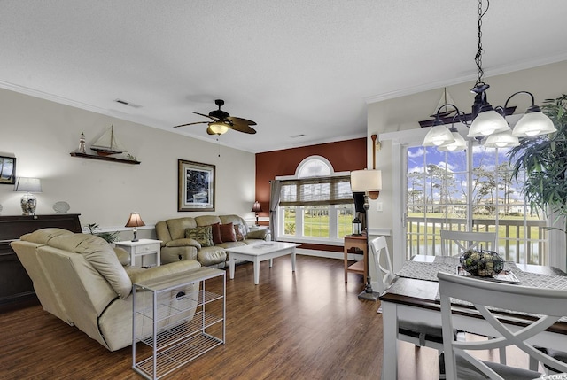 living room featuring visible vents, dark wood-style flooring, crown molding, and ceiling fan with notable chandelier