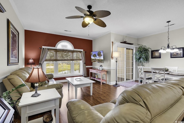 living room with crown molding, a textured ceiling, ceiling fan with notable chandelier, wood finished floors, and visible vents