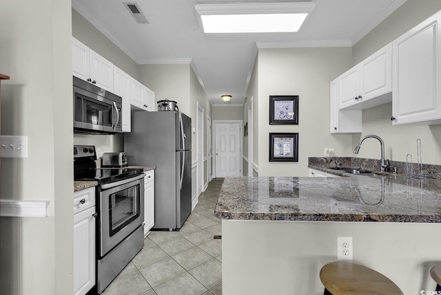 kitchen featuring a sink, a peninsula, dark stone countertops, and appliances with stainless steel finishes