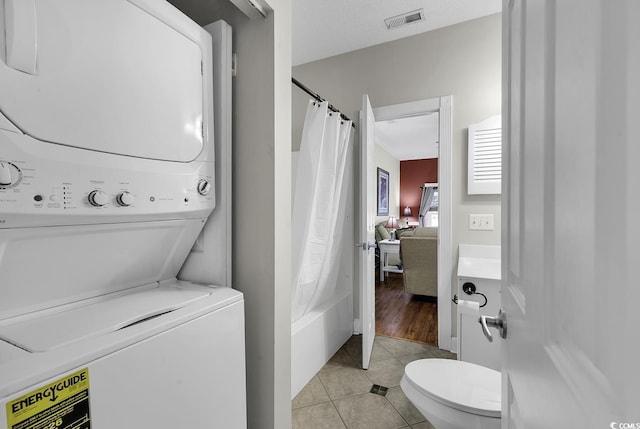 interior space featuring stacked washer and dryer, vanity, toilet, tile patterned floors, and visible vents