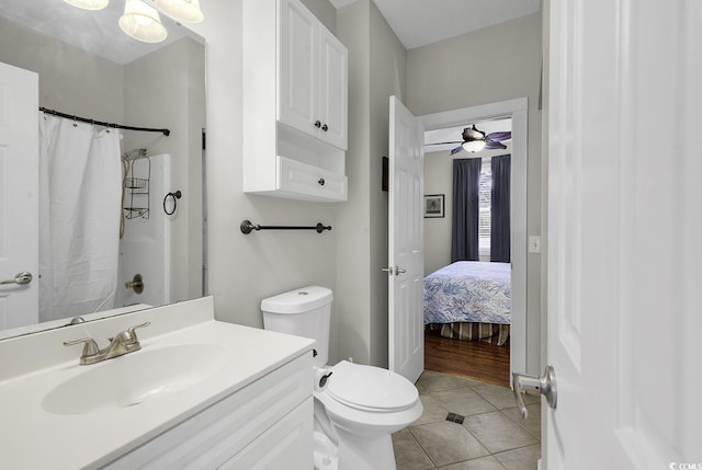 full bathroom with a shower with curtain, a ceiling fan, tile patterned flooring, vanity, and toilet