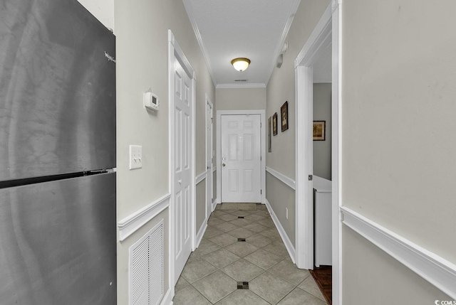 hallway with crown molding, tile patterned floors, and visible vents