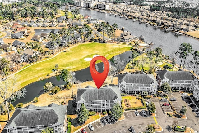 drone / aerial view featuring a water view, view of golf course, and a residential view