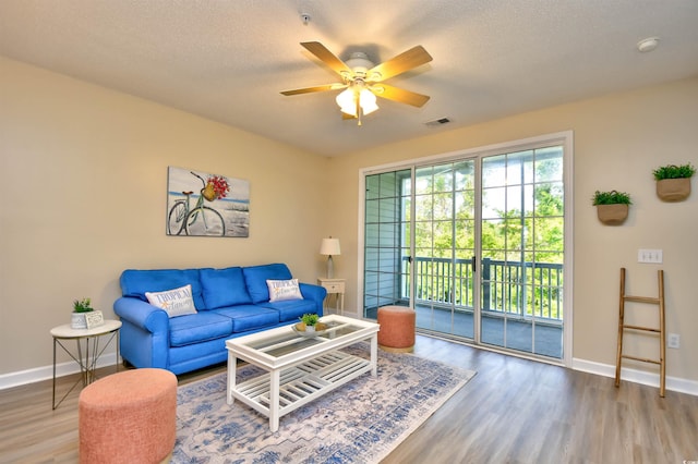 living room with baseboards, a ceiling fan, wood finished floors, and visible vents